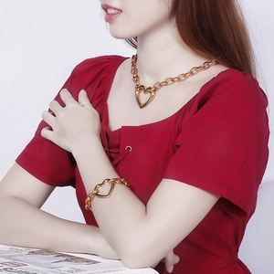Detail showing a chunky gold-tone heart necklace and bracelet set worn by a model
