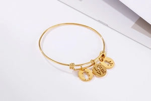Close-up of gold adjustable bangle with hollow girl pendants and LOVE engraved charm