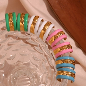 Close-up of C-shaped colorful enamel earrings set with gold wave texture on glass
