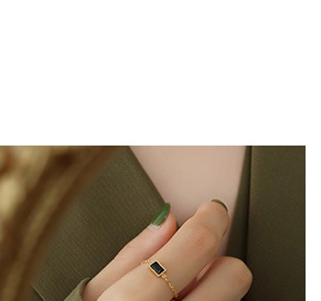 Detailed close-up of a 18K gold ring featuring a rectangular dark gemstone on a hand