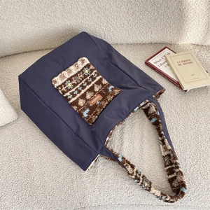 Detail of navy tote bag featuring floral plush pocket and woven brand label