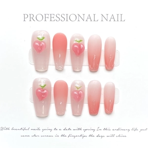 Detail of handmade press-on nails featuring 3D peach charms and pink gradient finish