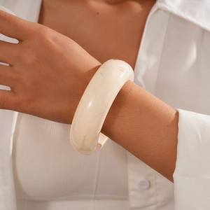 Close-up of a chunky cream resin bangle with marble texture on a model's wrist