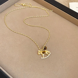 Detailaufnahme der goldenen Schaukelpferd-Halskette mit braunem Stein in Schmuckbox