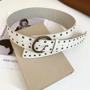 Detail of vintage cream leather belt with bronze rivets and a circular buckle on a gift box