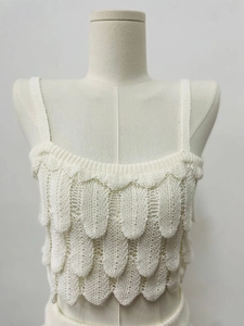 Detailed macro view of white layered knit crop top with feather-like scale textures