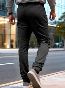 Dynamic street view of men's black quick-dry joggers with elastic cuffs and sleek texture