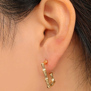 Bamboo style 14K gold plated titanium C-shape hoop earrings worn by a model