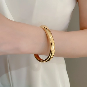 Polished gold tubular bangle with a high-shine mirror finish on model wrist