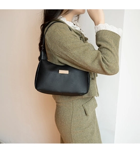 Close-up of black lychee grain leather hobo bag with gold metal plaque on model