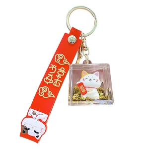 Japanese Maneki Neko keychain in gold glitter acrylic cube with red decorative strap