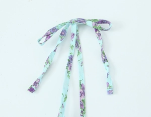 Detailed view of floral print poplin dress fabric with purple and green flowers
