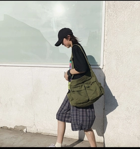 Detail of army green canvas crossbody bag showing large capacity and multi-pocket design
