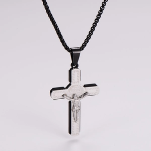 Gros plan du pendentif crucifix noir et argenté avec relief de Jésus sur une chaîne sombre