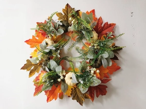Detailed view of autumn wreath with maple leaves, mini pumpkins, and white berries