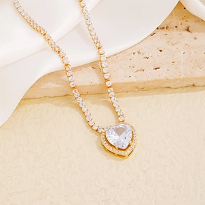 Elegant gold tennis chain necklace featuring a sparkling heart pendant on silk and stone