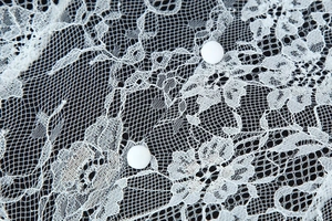 Gros plan sur la dentelle florale blanche avec boutons recouverts de tissu assortis