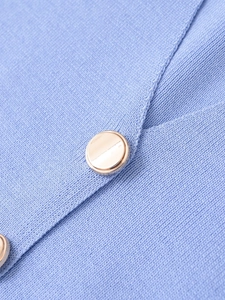 Gros plan sur la maille bleu clair et les élégants boutons ronds en métal doré