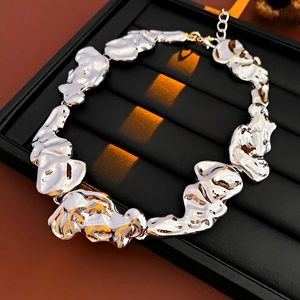 Detailed macro of silver irregular molten metal necklace on a black jewelry tray