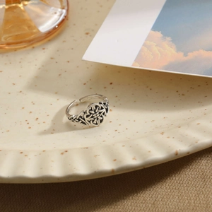 Macro shot of vintage silver Celtic knot ring detail on a textured beige display plate