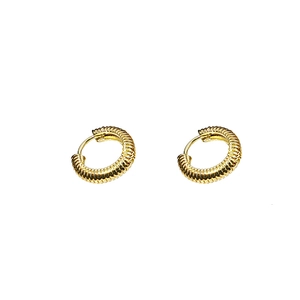 Gros plan détaillé de boucles d'oreilles créoles dorées avec texture en spirale et fini poli