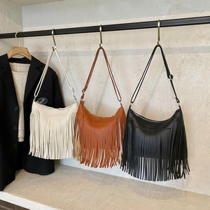 Three bohemian crescent bags with long fringe in cream, brown, and black colors