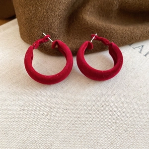 Gros plan sur des boucles d'oreilles créoles en velours rouge montrant la texture douce