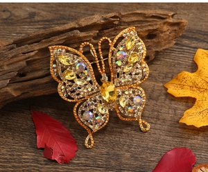 Vue macro de broche papillon vintage dorée avec strass jaunes sur un fond en bois sombre