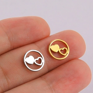 Stainless steel double heart hollow circular charms in gold and silver on a fingertip
