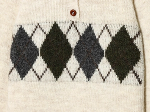 Detailed close-up of argyle knit sweater with green and grey patterns and a brown button