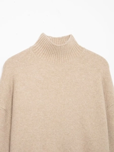 Vue détaillée du pull en maille beige à col montant avec texture fine et tissu doux