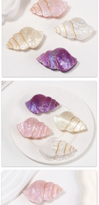 Detailed views of shell-shaped hair claws in pastel marble resin with gold trim