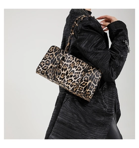 Close-up of a leopard print shoulder bag worn by a model in a black textured coat