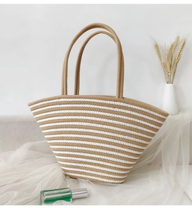 Handwoven straw tote bag with brown and white stripes in a casual vacation setting
