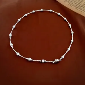French style pearl and silver bead necklace with luxury metal clasp on brown fabric