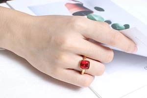 Detail of a square red zircon ring on model hand with a stylish gold plated finish