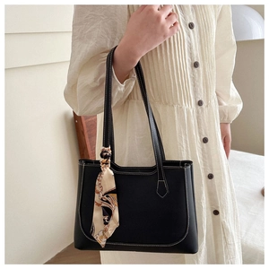 Sac cabas noir chic avec surpiqûres blanches et foulard en soie porté par un mannequin