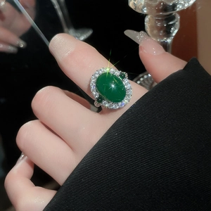 Détail d'une bague ovale luxueuse avec zircon vert émeraude portée au doigt du mannequin