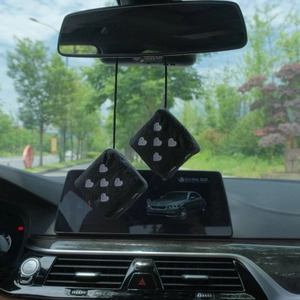Black plush car dice hanger with white heart embroidery on a rear-view mirror
