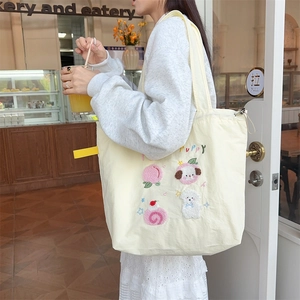 Detail of cute puppy embroidery and side adjustable straps on beige canvas tote bag