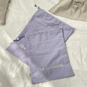 Macro shot of light purple drawstring storage bags with soft nylon texture on white linen