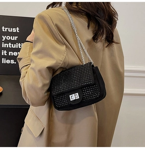 Detail of black rhinestone square bag with silver metal chain on camel coat