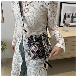 Ethnic knit bucket bag with colorful geometric patterns and leather drawstring detail