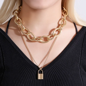 Detail of layered gold chunky chain and fine padlock pendant necklace on model