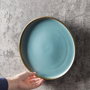 Minimalist matte blue ceramic dinner plate with gold rim on stone background