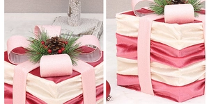 Macro detail of red Christmas gift box with pink ribbon, pine cones and berries