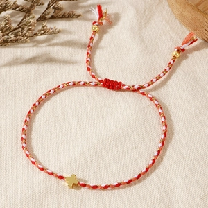 Detail view of woven tricolor handmade cord bracelet featuring a gold cross pendant