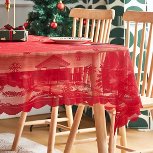Red rectangular Christmas lace tablecloth with snowflake and house patterns on wooden table
