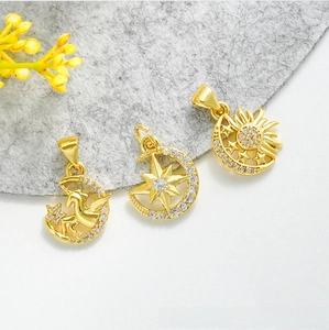 Détail de pendentifs lune dorés à l'or 18 carats avec motifs étoile, licorne et zircons blancs