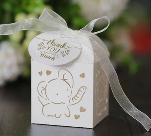 Detail of laser-cut elephant candy box with ivory ribbon and thank you tag for weddings